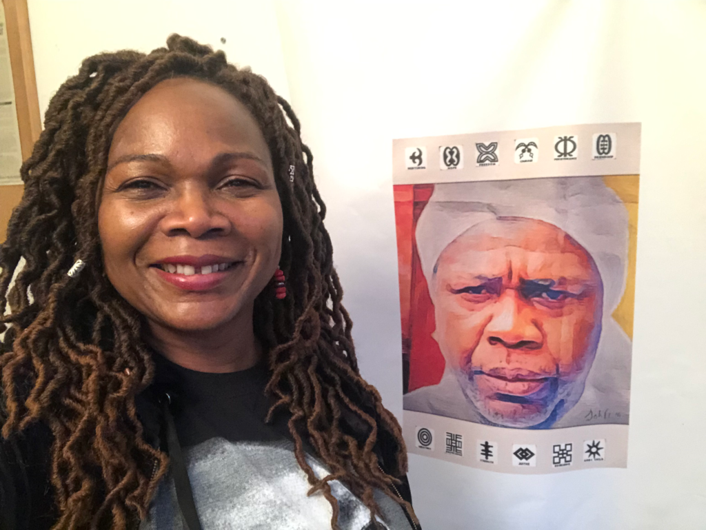 Josephine smiling next to a poster of Mighty Mouse John Oboh