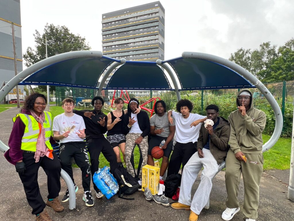 Eight young people sitting down in an urban environment with Josephine standing next to them